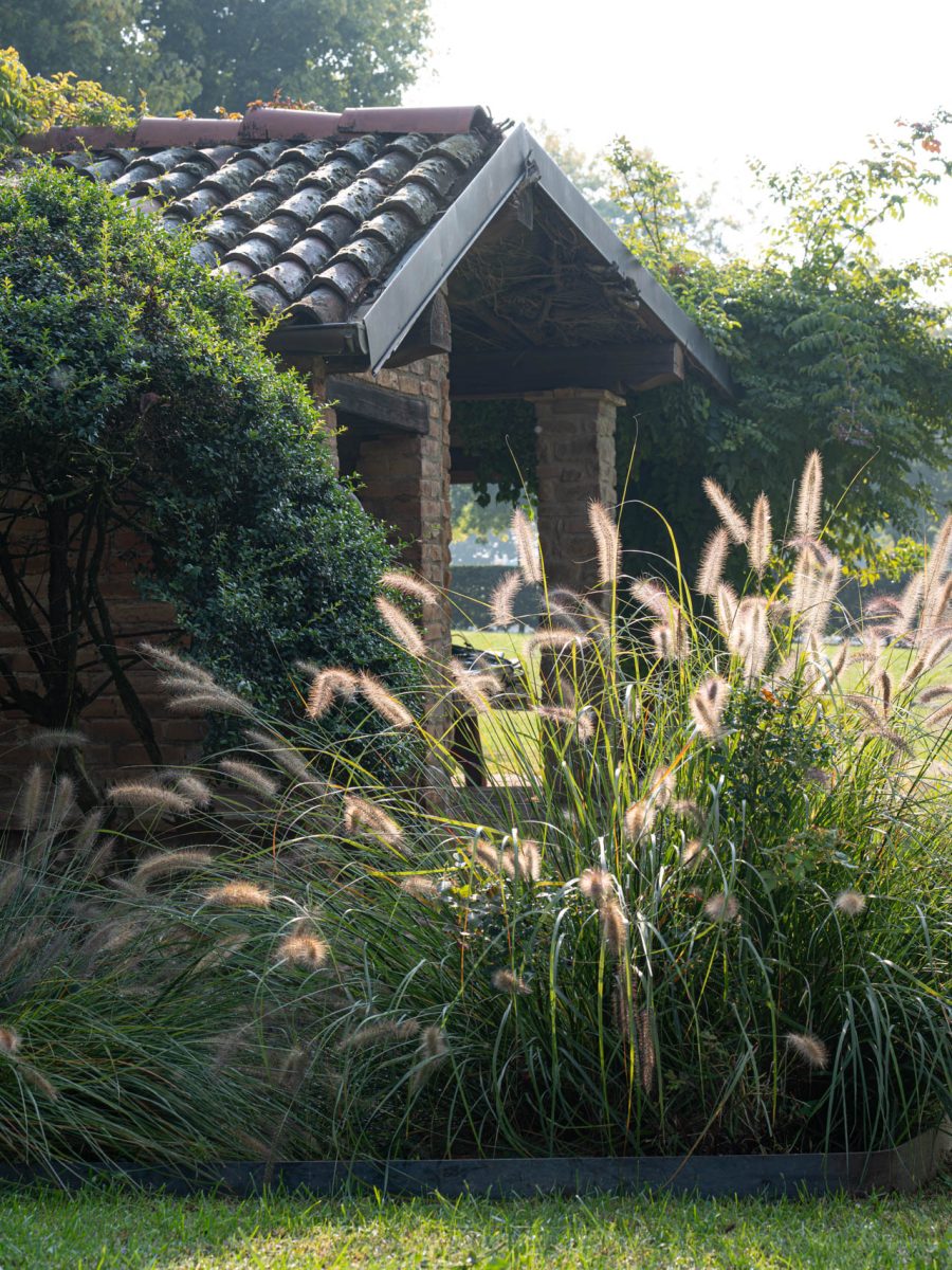 Padiglione in mattoni immerso nel verde, con Pennisetum ‘Hameln’ in veste autunnale nel giardino di Villa Silvia Sporthorses.
