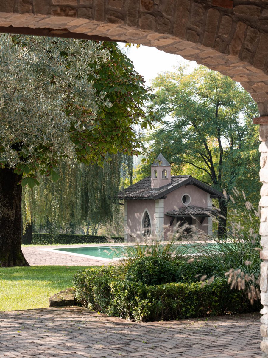 Giardino di uno château relais in Piemonte con piscina, bordura formale e cappella privata immersa nel parco.